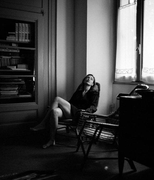 Woman in a graceful balancing pose in a minimalist dark room.